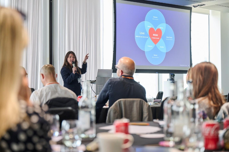 A person giving a presentation to a group of people

Description automatically generated